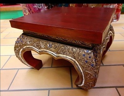 Cette élégante table sellette venue d’Inde. Son plateau en bois rouge et ses pieds finement décorés de motifs dorés et pierres bleues en font une pièce aussi décorative que fonctionnelle.  - Dimensions : H 23 cm × L 13 cm   - Matériau : bois sculpté et décoré à la main   - Prix : 80,00 € TTC