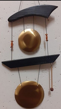 Carillon Indien – 20,00 €   Son gong doré suspendu entre deux arcs en bois noir diffuse une sonorité douce et méditative.  H : 61 cm   📐 L : 11,5 cm 🔔 Gong central doré aux vibrations apaisantes 🌿 Structure en bois noir sculpté