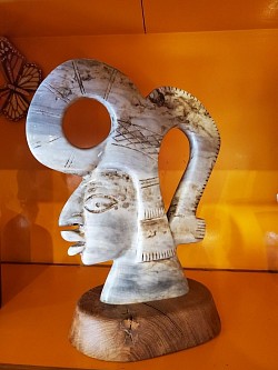 Tête Maya en Jaspe Gris – Sculpture Unique   Cette pièce sculpturale captivante représente une tête maya stylisée, taillée dans un jaspe gris aux nuances marbrées.  🔸 Socle : Bois naturel   📐 Hauteur 31 cm · Longueur 23 cm    Prix : 240,00 €