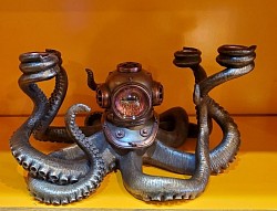 Bougeoir Pieuvre – Élégance steampunk en métal.  Sculpté dans un style steampunk avec ses détails mécaniques, engrenages et tentacules enroulés,  dimensions: 30 cm de long × 25 cm de large  💰 : 200,00 €