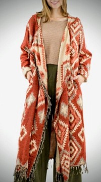 Ce manteau aux motifs jacquard géométriques. Ses franges dansantes et sa capuche protectrice évoquent les grands espaces . Confectionné en acrylique doux. Tailles : S/M et L/XL